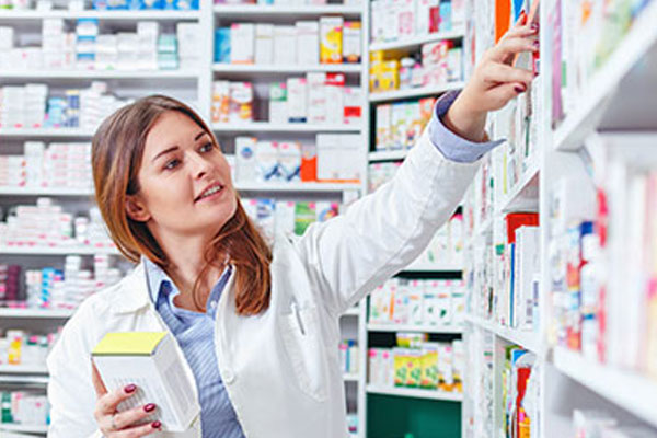 Pharmacist reaching for some tablets in a pharmacy